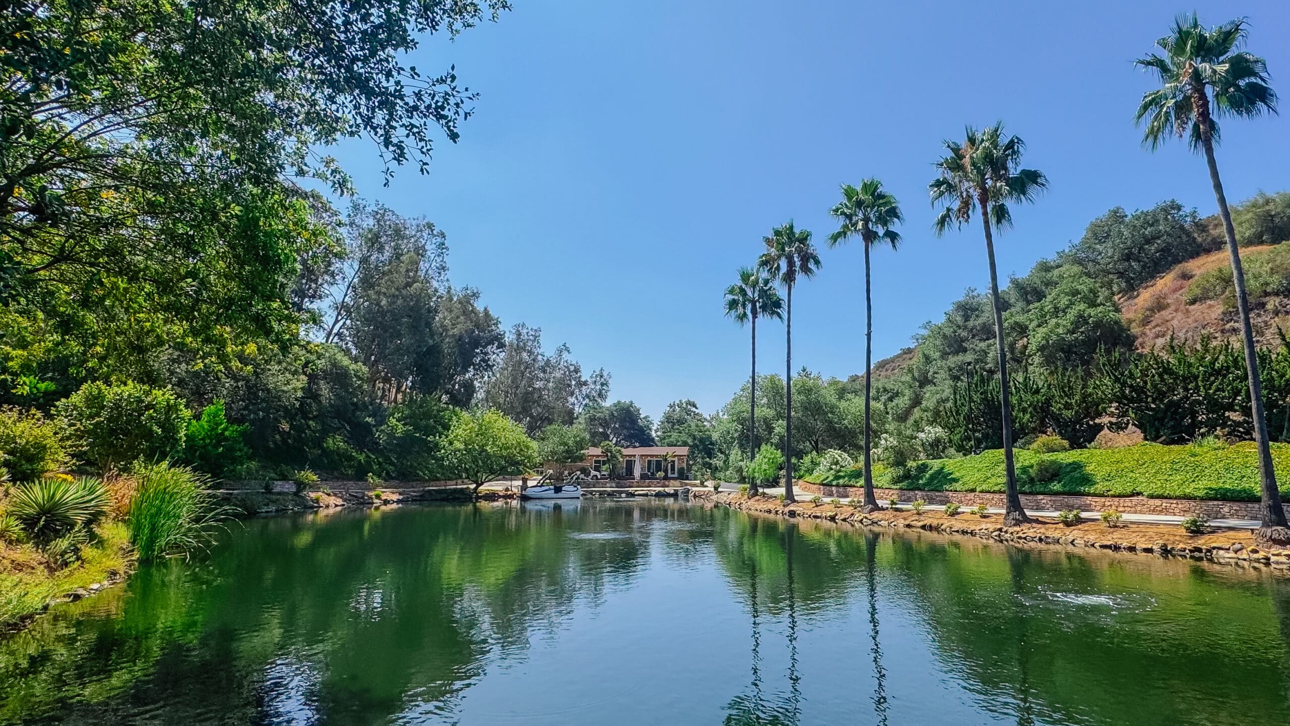 Scenic green, tree-lined lake at Los Willows Estate in Fallbrook, California, surrounded by lush landscaping and tranquil natural beauty.