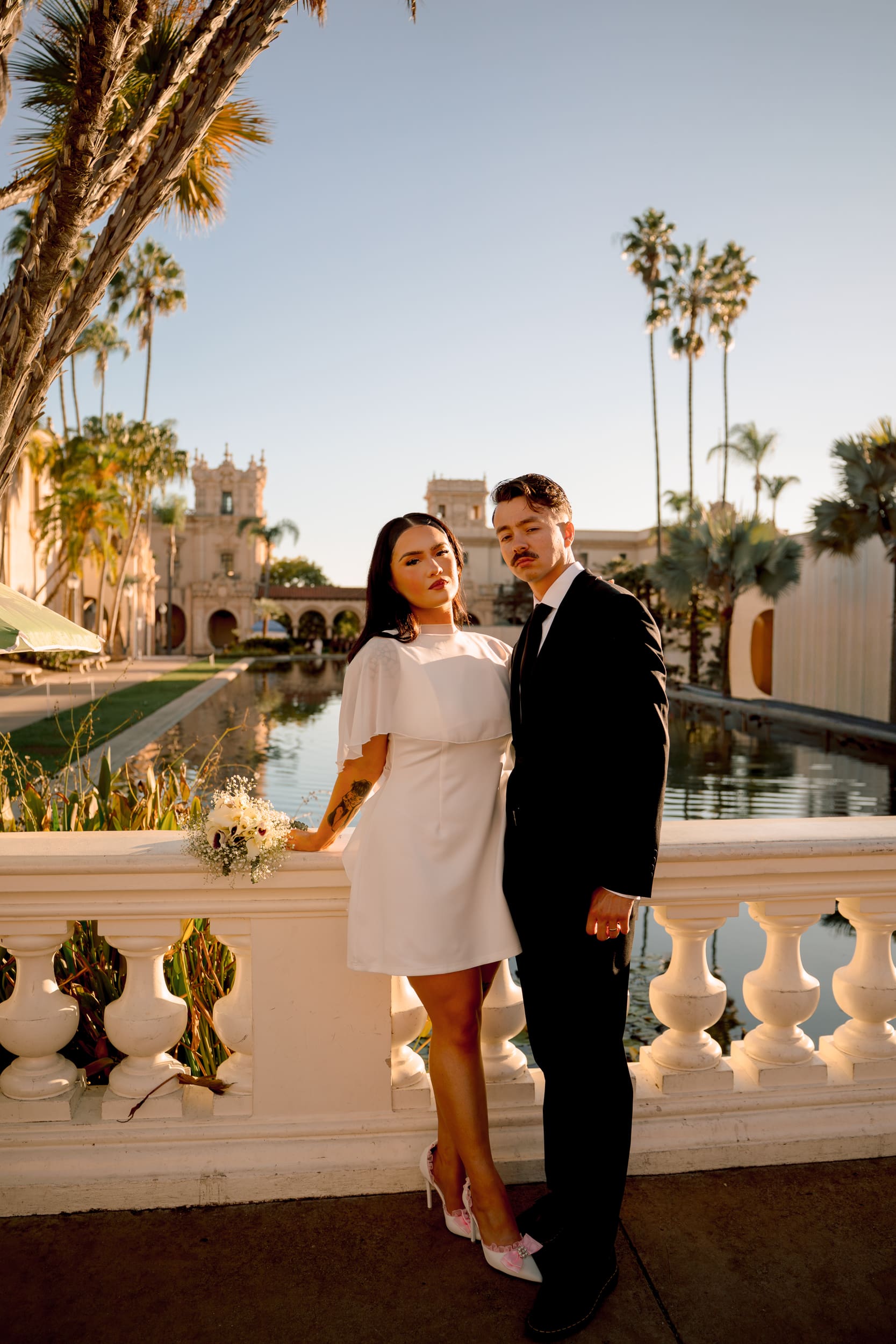 Bride and groom standing by the reflecting pool at Balboa Park at golden hour during their San Diego courthouse wedding portraits, photographed in a cinematic true-to-color style.
